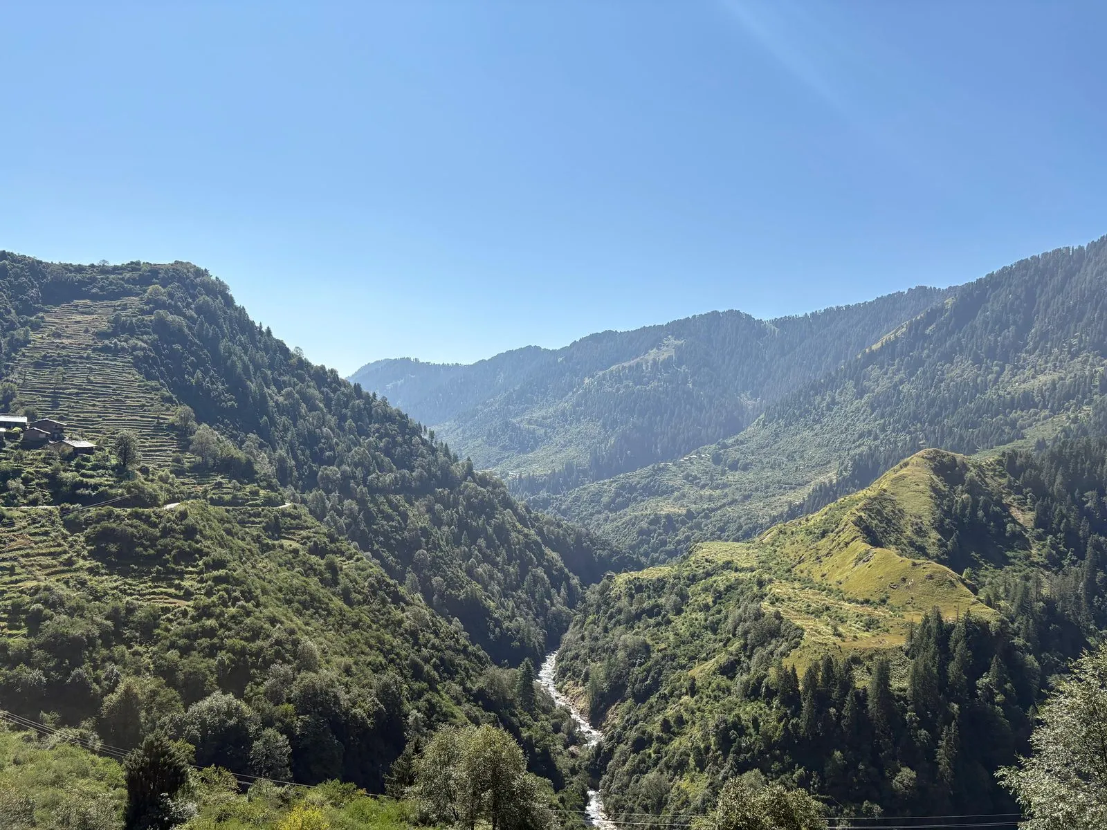 A river threading through a deep forested gorge, terraced slopes on either side